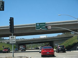 After this traffic signal, the next left connects to Interstate 5 south. Continue straight ahead into the Del Mar Terraces neighborhood of San Diego, with a view of Los Peñasquitos Lagoon on the south side of Carmel Valley Road.