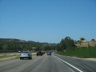 The concrete pavement changes to asphalt as California 56 passes by the location where California 56 used to transition directly onto Carmel Valley Road. The sound wall on the north side of the freeway partially blocks access to Old Carmel Valley Road, which used to serve as the direct connection from California 56 to Carmel Valley Road before the 56 gap between Exit 3 and Exit 6 was filled in July 2004.