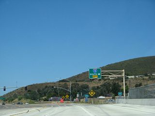 Westbound California 56 (Ted Williams Freeway) reaches Exit 9A, Interstate 15 south. A pair of neutered freeway entrance shields guard the transition ramp.