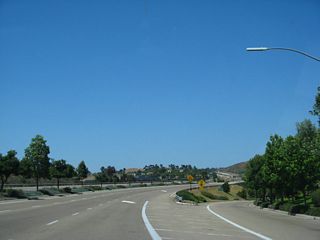 Reaching the off-ramp for Rancho Carmel Drive and Sabre Springs Parkway, the landscaped median comes to an end, and the right lane ends. The city of San Diego section of parkway ends after this interchange.