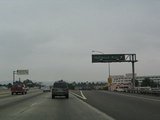 Northbound California 57 (Orange Freeway) reaches Exit 7, Nutwood Avenue. Some of the highway signs along California 57 between Fullerton and Pomona date back to the original construction of the freeway, and these signs really show their age. This particular sign, which is found along northbound as it reaches Exit 7/Nutwood Avenue, is an example of that older generation of sign. The sign is fairly dirty and has not been cleaned in some time.