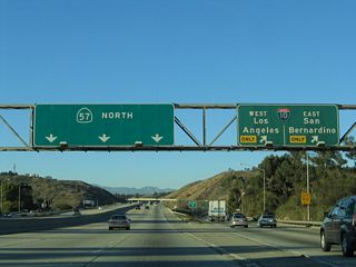 Northbound California 57 (Orange Freeway) meets Exit 21, Interstate 10 (San Bernardino Freeway). The maze of ramps associated with the massive Kellogg Interchange is not as noticeable on northbound California 57, since the Orange Freeway serves as the top deck in the symmetrical stack interchange. However, the view of this interchange from the lowest level (Interstate 10) betrays the severe height difference between these two intersecting freeways. In addition, California 71 (which is not mentioned along northbound California 57) enters the Kellogg Interchange from the southwest, adding more ramps to the stack.