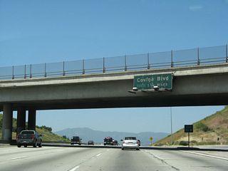 This porcelain enamel sign is the first to advise travelers on California 57 north (former Interstate 210 west) for the next interchange: Exit 24A, Covina Boulevard.