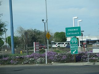 A California 99 north freeway entrance shield assembly is posted on the north side of V Street at the 14th Street intersection. A busy freeway known as "California's Work Horse" due to its high traffic volumes and significant truck traffic, California 99 travels northwest toward Modesto, then turns north toward Manteca, Stockton, and Sacramento.