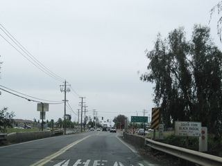 Continuing south, California 59 enters suburban Merced. A series of cross streets and traffic signals ensues. Here, California 59 crosses over the South Fork Black Rascal and proceeds toward an intersection with Merced County J-7 (Santa Fe Drive) and West Olive Avenue.