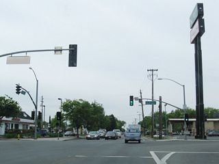 Southbound California 59 meets 13th Street at this traffic signal. Turn left for California 59 south, California 99 south, and California 140 east. Turn right for California 140 west. Continue straight ahead for V Street south.