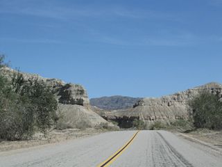 The twisting rock formations add a colorful look to Box Canyon, especially around sunset. Along the south side of the highway is Sheep Hole Oasis.