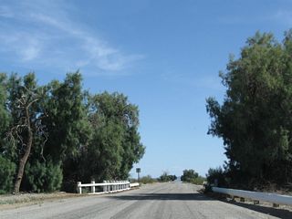 Historic U.S. 60-70 east along Chuckwalla Road crosses a third wash bridge with white wooden railing.