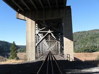 Four steel truss segments span lengths of 360, 432, 576, and 432 feet each. Three concrete piers support the bridge above the river. A comparable bridge from the same era is the Interstate 5 (U.S. 99) Pit River bridge over Lake Shasta.⁷⁸