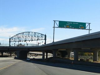 A closer look reveals that the two left lanes of the off-ramp will connect to Taylor Street west, while the right lane connects to Taylor Street east. All movements at this intersection are controlled by the single set of traffic signals on the truss span. Use Taylor Street east to First Street north to the San Jose Civic Center complex.