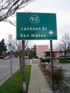 Near the east end of SR 92 in Downtown Hayward, this trailblazer is posted on westbound Fletcher Lane at Watkins Street. The connection from SR 238 north to SRa 92 west requires a detour via Fletcher Lane and Watkins Street because of a left turn restriction.