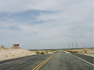This Bureau of Land Management sign advises that California 98 is leaving the Yuha Desert area. A final blue flag waves in the air, followed by the appearance of several power lines in the distance.