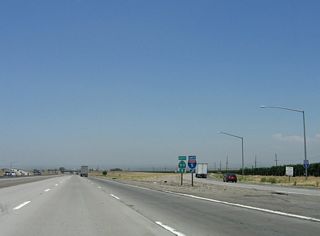 The main lanes of California 99 continue straight ahead, while the lanes carrying Interstate 5 sweep to the right and then over California 99. A pair of trailblazers, one for Interstate 5 and the other for California 99, is posted at the gore point for Exit 221. By 2011, these route markers had been replaced, with the new Interstate 5 sign neutered. If designated as an Interstate, this split would be the southern terminus of Interstate 7 or 9.