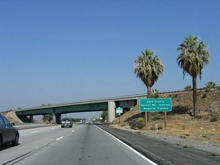 In Kern County, California 99 is known as the Kern County Korean War Veterans Memorial Highway, in addition to its more well-known designations as the Golden State Highway and Main Street of California. Behind this sign is the overpass carrying northbound Interstate 5 traffic over the California 99 main lanes.