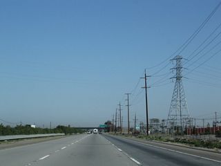 A 230kV Pacific Gas and Electric power line passes overhead and terminates in a substation located on the east side of the freeway.