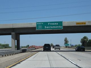 An overhead pull-through sign, mounted on the California 46 overpass, indicates that California 99 north travels north to Fresno and Sacramento.