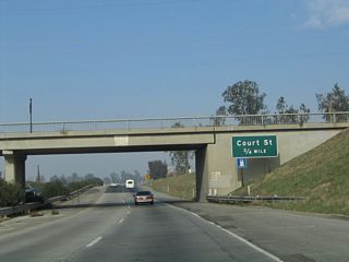 While passing under Avenue 96, this sign announces that the next exit along California 99 north is Exit 70B, Court Street (three-quarters of a mile). This sign has since been replaced with a reflective sign that includes the exit number.