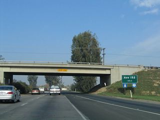 The next exit along California 99 north is Exit 77, Avenue 152 (Olive Street), one mile. This exit serves the community of Tipton, the majority of which is located to the east of the freeway. This sign was replaced by 2010.