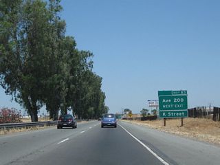 Northbound California 99 approaches Exit 83, Avenue 200. Originally, the California 99 business route had its own dedicated off-ramp that led from California 99 north directly onto K Street. That connection is now made via Avenue 200 west to K Street north. The former off-ramp (Exit 84) has been eliminated completely. Based on our drive along K Street and J Street, which combined form the business route, there are few if any remaining business route signs. However, there are occasional signs for Historic U.S. 99.