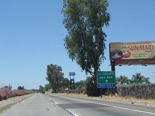 Northbound California 99 meets Exit 109, Tulare County J-38 (Avenue 384) and Rest Area. Note the billboard advertising the Sun-Maid Raisins Visitors Center, which is located four miles ahead in Fresno County at Exit 114, Bethel Avenue.