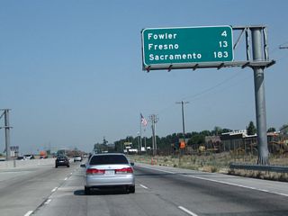 Leaving the California 43 interchange behind, this mileage sign along California 99 north provides the distance to Fowler (four miles), Fresno (13 miles), and Sacramento (183 miles). When the third lane was added through this area between Selma and Fowler, this sign was elevated and moved onto a sign bridge.