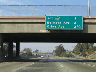 Another mileage sign for upcoming exits from California 99 north is posted right at the gore point for Exit 132B. The next three exits are Exit 133, California 180 (Sequoia-Kings Canyon Freeway) east and west; Exit 134, Belmont Avenue; and Exit 135A, Olive Avenue.