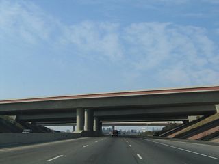 California 99 passes under California 180. Note the common design features for many of the freeway interchanges in Fresno, including the notable red-brown horizontal line that offers relief to the concrete bridge.