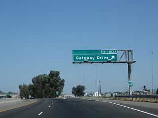 Northbound California 99 (Golden State Highway) reaches Exit 153A, California 99 Business (Gateway Drive).