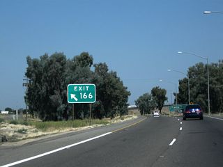 A very large gore point sign is posted for Exit 166.
