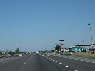 Northbound California 99 approaches the right turn to Harvey Pettit Road. A truck stop is located at this intersection.