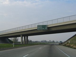 Passing under Bradbury Road, this mileage sign provides the distance to Turlock (four miles), Modesto (18 miles), and Sacramento (92 miles).