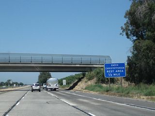 The next exit along California 99 (Golden State Highway) north is Exit 210, Enoch Christoffersen Safety Rest Area (one-half mile). Facilities include restrooms, pet walking area, parking, and related facilities. Shortly after this sign and before the rest area, California 99 will leave Merced County and enter Stanislaus County.