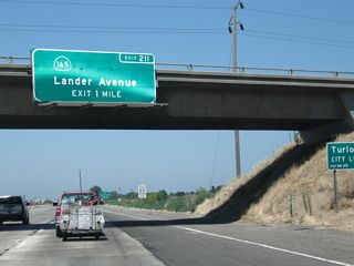 The next exit along California 99 north is Exit 211, California 165 (Lander Avenue) south and Stanislaus County Route J-14 (Lander Avenue) north into Turlock. CR J-14 travels north to meet California 99 Business in downtown Turlock, while California 165 heads south toward Los Banos and a junction with Interstate 5 at the Los Banos exit some nine miles south of the city. While California 99 passes through town after town, Interstate 5 avoids nearly all of them between Wheeler Ridge and Tracy.
