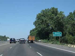The next three exits along California 99 north all serve the city of Ripon: Exit 236, Main Street; Exit 237A, Milgeo Avenue; and Exit 237B, San Joaquin County J-5 (Jack Tone Road). After this sign, California 99 will cross the Stanislaus River into San Joaquin County and the city of Ripon.