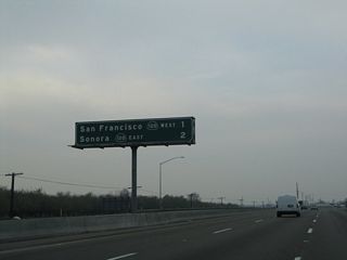 A mileage sign along California 99 north provides the distance to Exit 241, California 120 freeway west to Manteca, Tracy, and San Francisco and Exit 242, California 120 east to Oakdale and Sonora. Omitted from this sign is Exit 240, Austin Road.