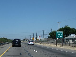 Northbound California 99 meets Exit 251, Clark Drive. If California 99 were to be upgraded to Interstate standards, sharp right turn exits such as this one may have to be upgraded to modern standards.