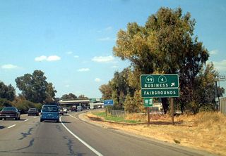 Mariposa Road serves as the southernmost segment of the business route for California 99. It is unusual to see business route signs that feature shields on the freeway; the normal standard is for such signage to be text only. Notably, this sign mentions California 4 Business; since California 4 was rerouted onto the Crosstown Expressway, a business route was commissioned along its original route via Charter Way. Following northbound California 99 Business and San Joaquin County Route J-7 connects with Charter Way as a more direct route to California 4 Business (Charter Way). This sign was gone by 2011.