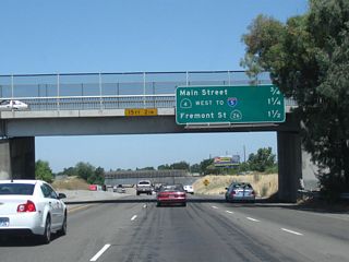 As traffic from California 4 west merges onto California 99 north, this mileage sign provides the distance to the next three exits: Exit 253, Main Street; Exit 254A, California 4 (Crosstown Freeway) west, and Exit 254B, California 26 (Fremont Street) east. If the Crosstown Freeway is extended east of California 99 someday, California 4 would be rerouted onto that freeway, and the existing sections on Farmington Road would likely become part of California 4 Business.