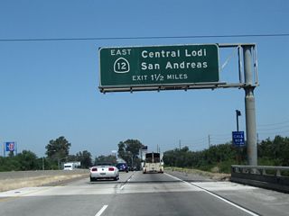 The next exit along California 99 north is Exit 266, California 12 (Victor Road) east to San Andreas. This sign is mounted on the California 99 bridge over Kettleman Lane. Ahead, traffic from California 12 east will merge onto California 99 north.