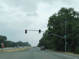 Northbound California 99 meets Estates Drive at this traffic signal. Turn left for Estates Drive south into the Butte Creek Country Club. California 99 proceeds northwest toward the city center of Chico. Ahead, the southbound lanes of California 99 are concrete, and the northbound lanes are asphalt. This configuration will continue north until the Southgate Avenue and Entler Avenue intersection.