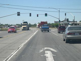 Northbound California 99 approaches a signalized intersection with Garner Lane. Land at the northeastern corner of this intersection was previously set aside for an interchange on a once-proposed easterly alignment of California 99 that was never constructed.