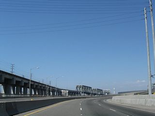 SR 103 (Terminal Island Freeway) curves northeast away from the Alameda Corridor with three northbound lanes. SR 47 branches northward from SR 103 along Henry Ford Avenue to connect with Alameda Street to Carson and Compton.