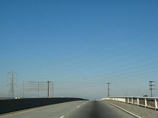 California 103 angles northeast between the refineries and industrial areas onto the Anaheim Street overcrossing, a viaduct spanning a railroad yard, Anaheim Street and Southern Pacific Drive.