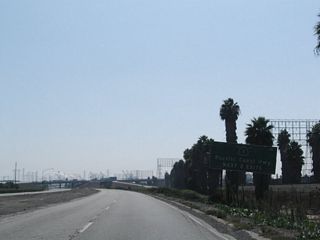 Unnumbered exits as a cloverleaf interchange join SR 103 (Terminal Island Freeway) south with SR 1 (Pacific Coast Highway) north and south. This sign was gone by 2009.