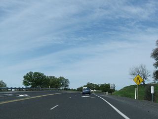 The Sonora Bypass carries California 108 around the city of Sonora. Originally built in 1987 as an at-grade, two-lane highway between California 49 and Mono Way (California 108 Business), the bypass was extended from Mono Way to Peaceful Oak Road (Standard Road) in July 2004. Plans call for a further extension east from Peaceful Oak Road to Via Este in 2011, and a third segment from that point east to Soulsbyville Road near the base of the Twain Harte Grade is scheduled for construction thereafter, pending funding identification. This photo shows the eastern beginning of the Sonora Bypass (also called the Sonora Bypass East) as of 2009 leaving Peaceful Oak Road (Standard Road). For now, the bypass uses the eastbound lanes, meaning the first postmile on the bypass is shown with a "T" prefix (for "temporary").