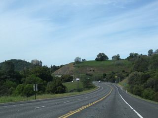 Continuing downhill, a climbing lane assists eastbound traffic en route to Mono Way. Ahead, westbound California 108 (Sonora Bypass) approaches Lime Kiln Road and Washington Street (0.25 mile), a signalized intersection.