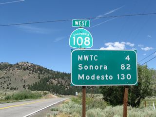The first westbound reassurance shield for California 108 is posted along with a mileage sign that provides the distance to the Marine Corps Training Center (four miles), Sonora (82 miles), and Modesto (130 miles).
