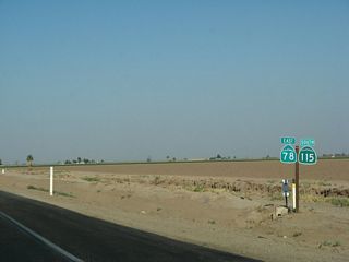 California 78 east and California 115 south overlap for a short distance, as marked by this reassurance shield east of Brawley. California 115 stays well to the east of Brawley and thus avoids any developed areas until reaching Holtville.