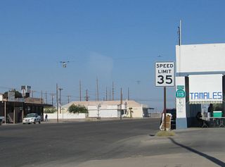 A California 115 shield is posted on the side of a building in downtown Calipatria where the route begins.