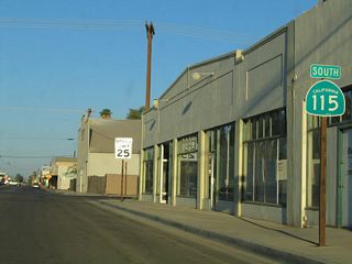 This reassurance shield is posted after the jog from Palm Avenue. The stop sign ahead is the pending junction with Imperial County Route S-32 (Orchard Road). Orchard Road travels south from downtown Holtville to meet Interstate 8, where it transitions directly onto California 7 expressway. California 7 in turn travels south to the Calexico East Port of Entry.